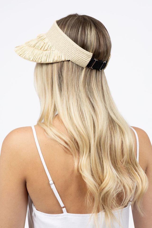 Woman wearing a beige visor with a plain background