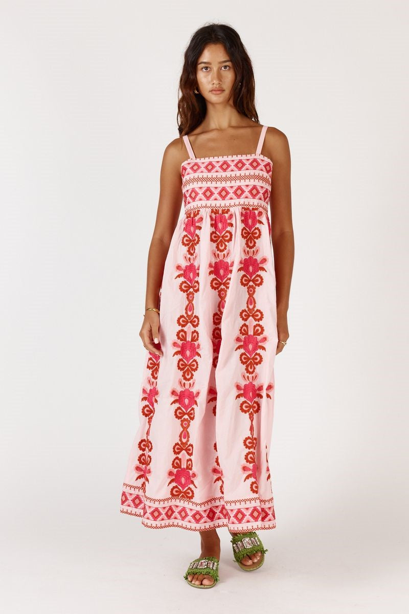 Woman wearing a long, white dress with red floral patterns on a white background