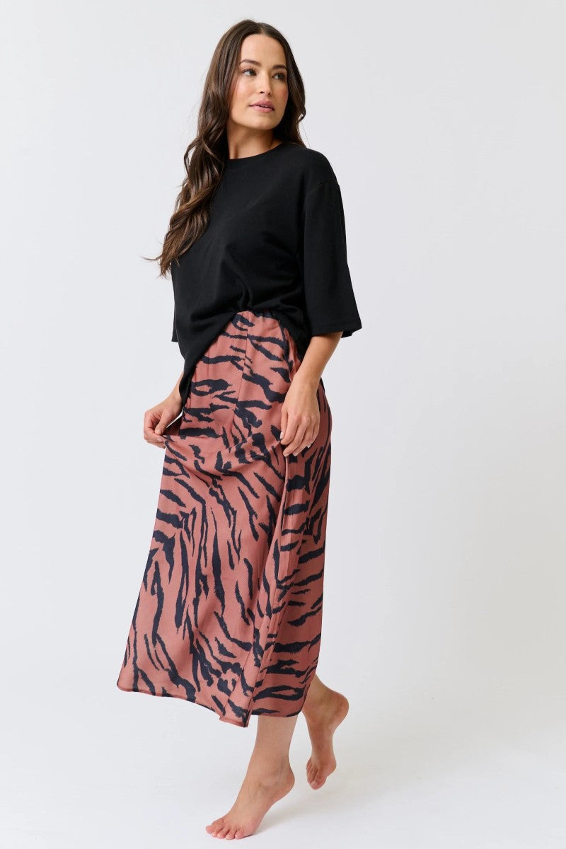 Woman wearing a black top and pink tiger print skirt on a white background