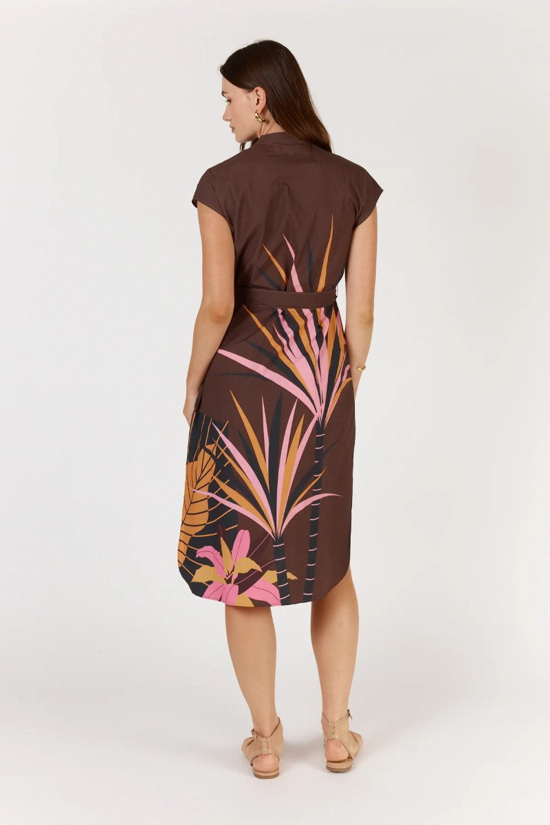 Woman wearing a brown dress with tropical leaf pattern on a white background