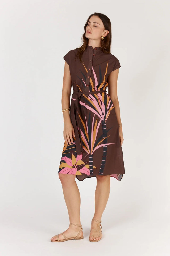 Woman wearing a brown dress with pink floral patterns on a white background