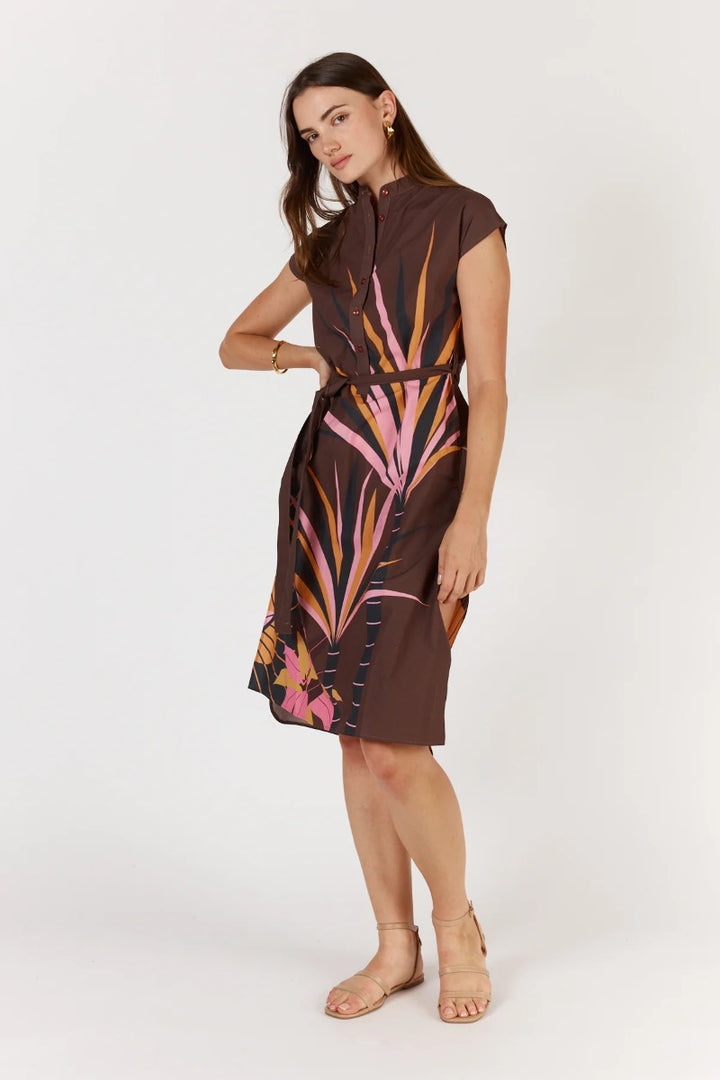 Woman wearing a brown dress with colorful abstract pattern on a white background