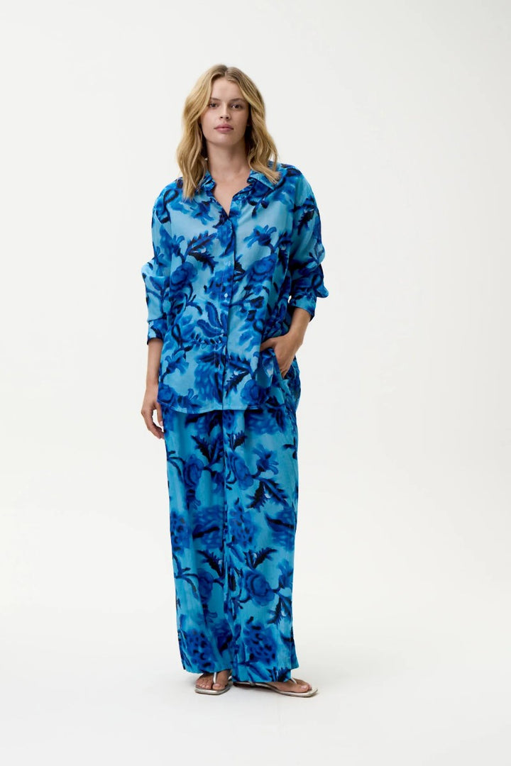 Woman wearing a blue floral pajama set on a white background