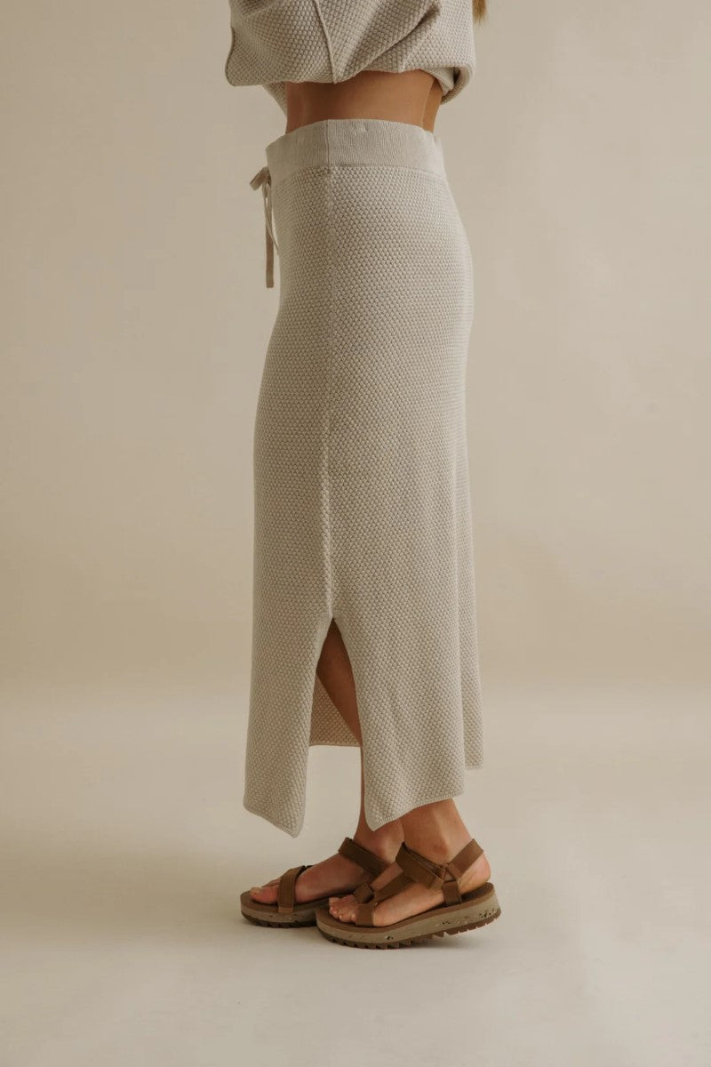 Person wearing a textured beige skirt with a neutral background