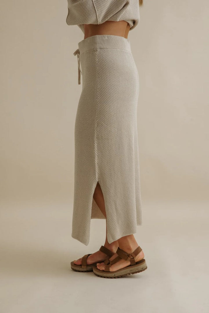 Person wearing a textured beige skirt with a neutral background