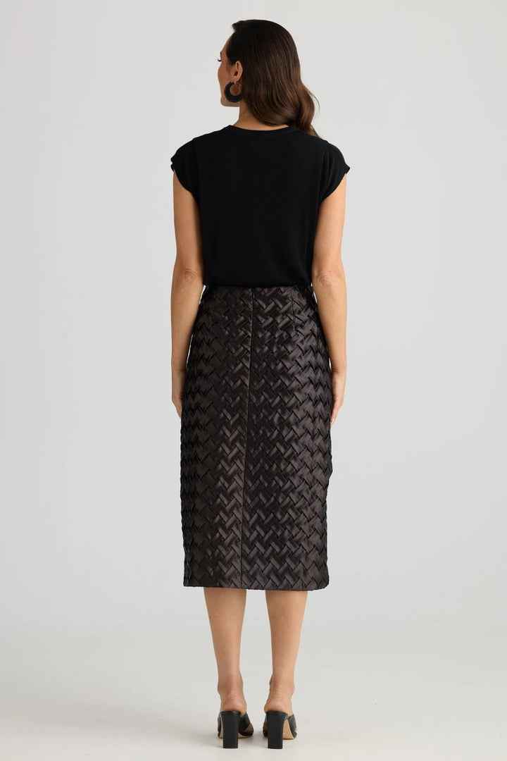 Woman wearing a black patterned skirt and black top on a white background