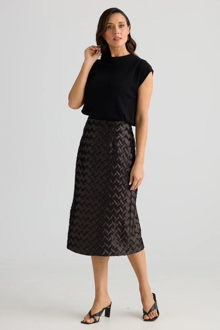 Woman wearing a black top and patterned skirt on a white background