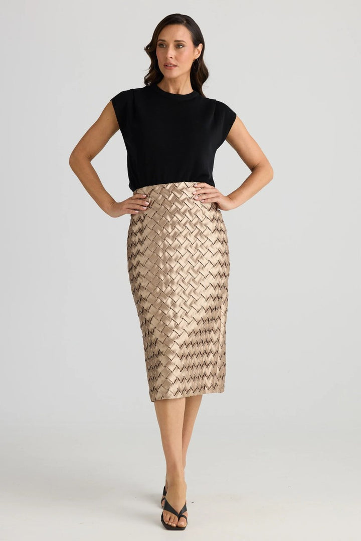 Woman wearing a black top and patterned beige skirt on a white background