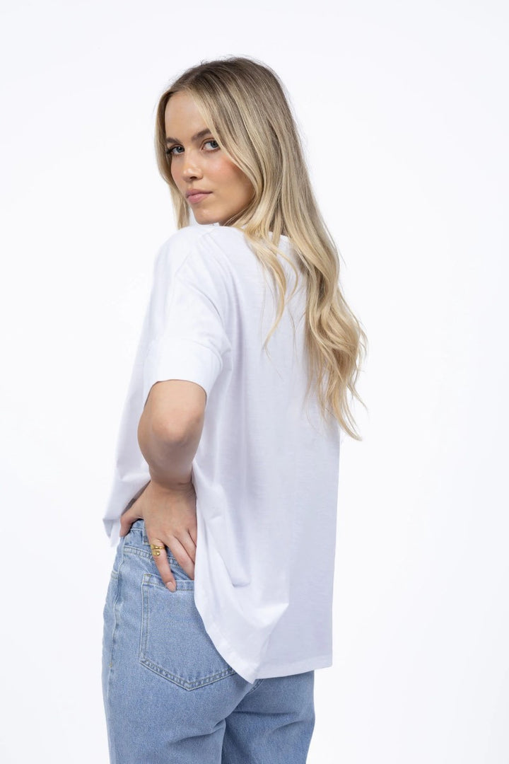 Woman wearing a white oversized shirt and light blue jeans on a white background