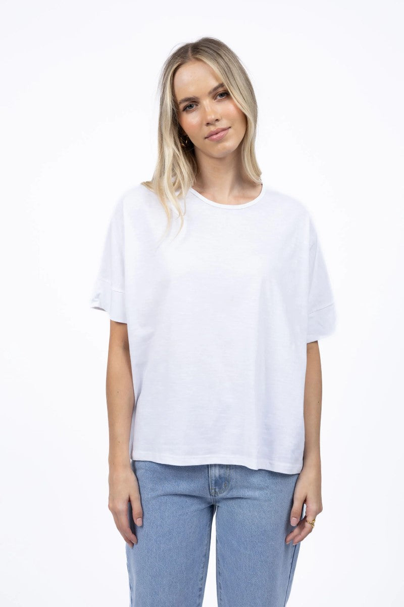 Woman wearing a plain white t-shirt and light blue jeans on a white background