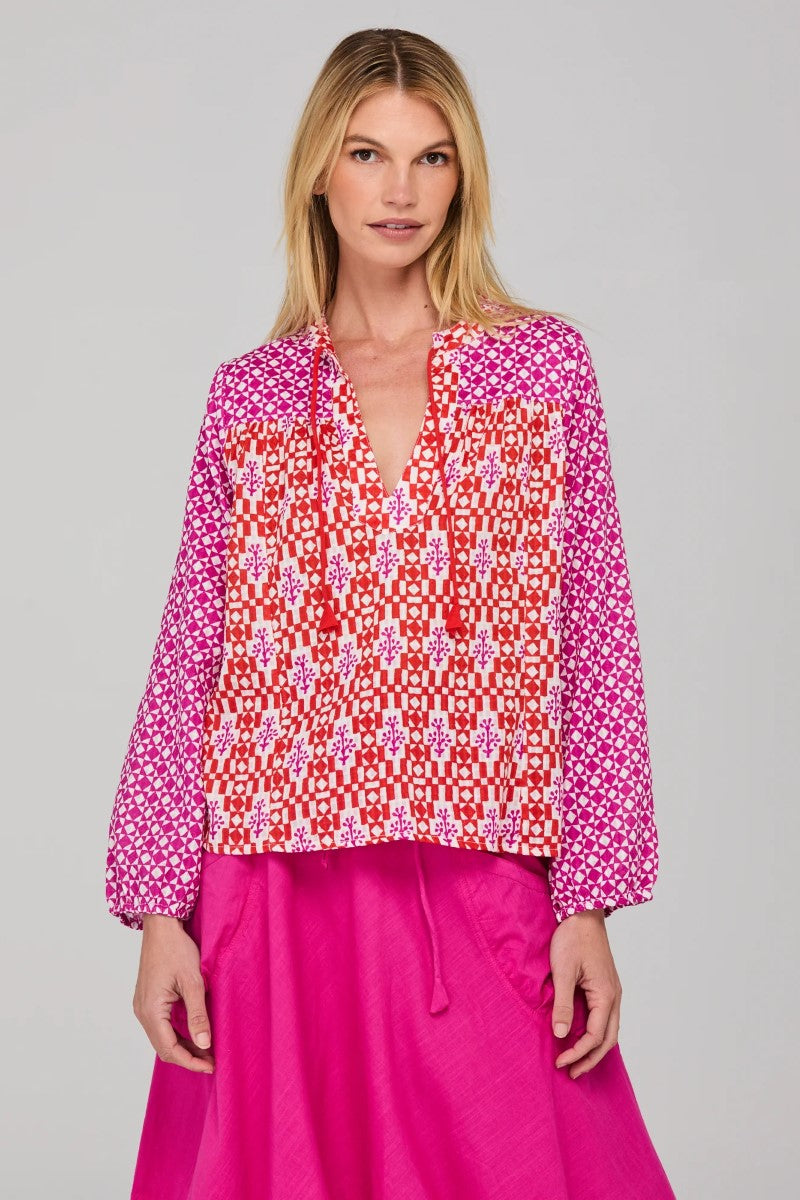 Woman wearing a patterned blouse and pink skirt on a gray background