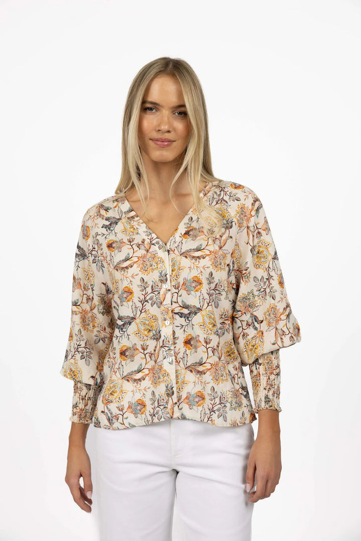 Woman wearing a floral blouse with white pants on a white background