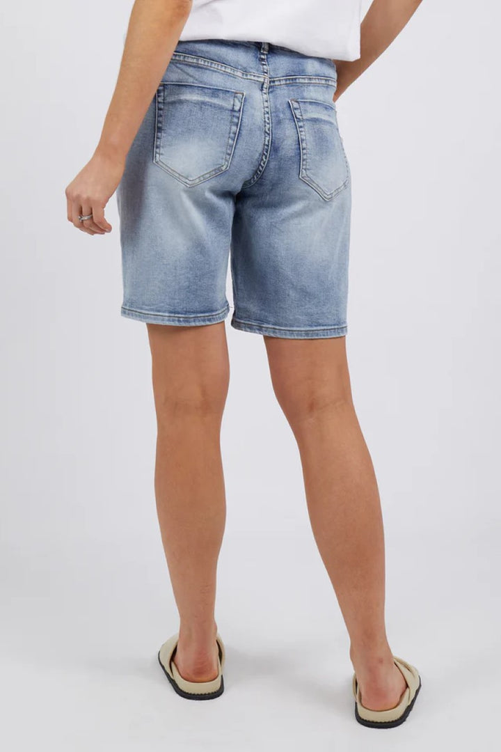 Person wearing light blue denim shorts on a white background