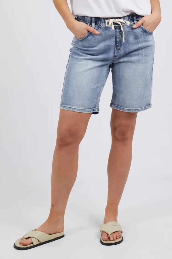 Person wearing light blue denim shorts on a white background