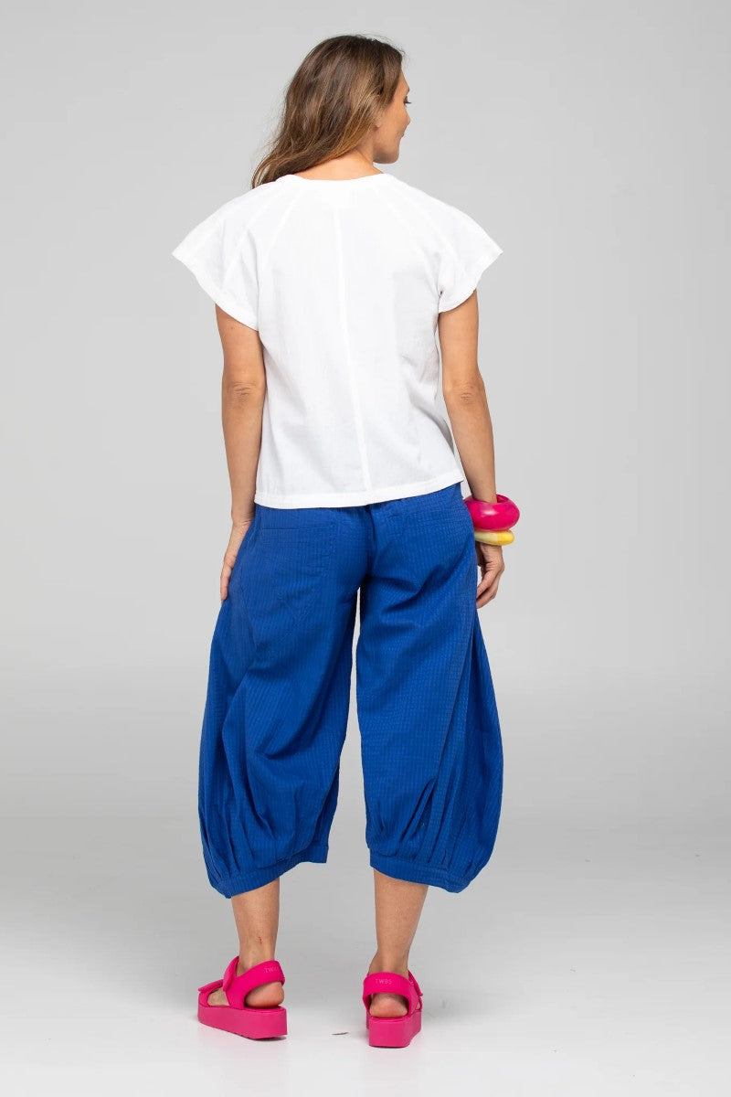 Woman wearing a white top and blue pants on a gray background