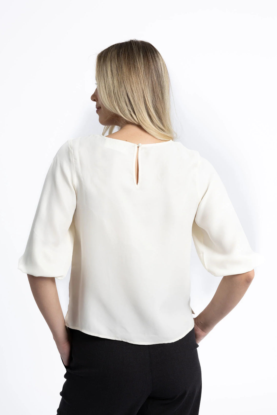 Woman wearing a white blouse with a V-neckline on a white background