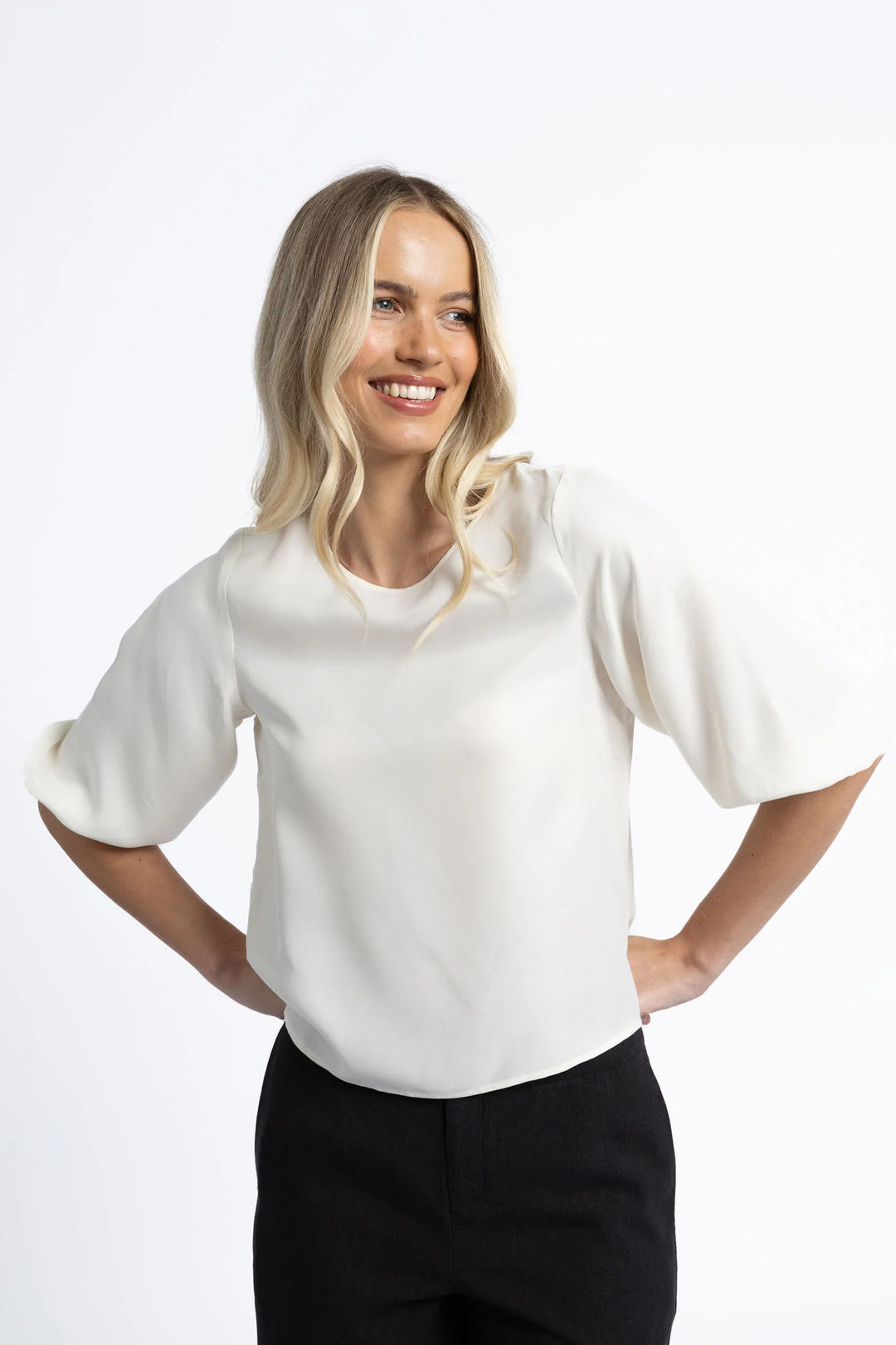 Woman wearing a white blouse and black pants on a white background