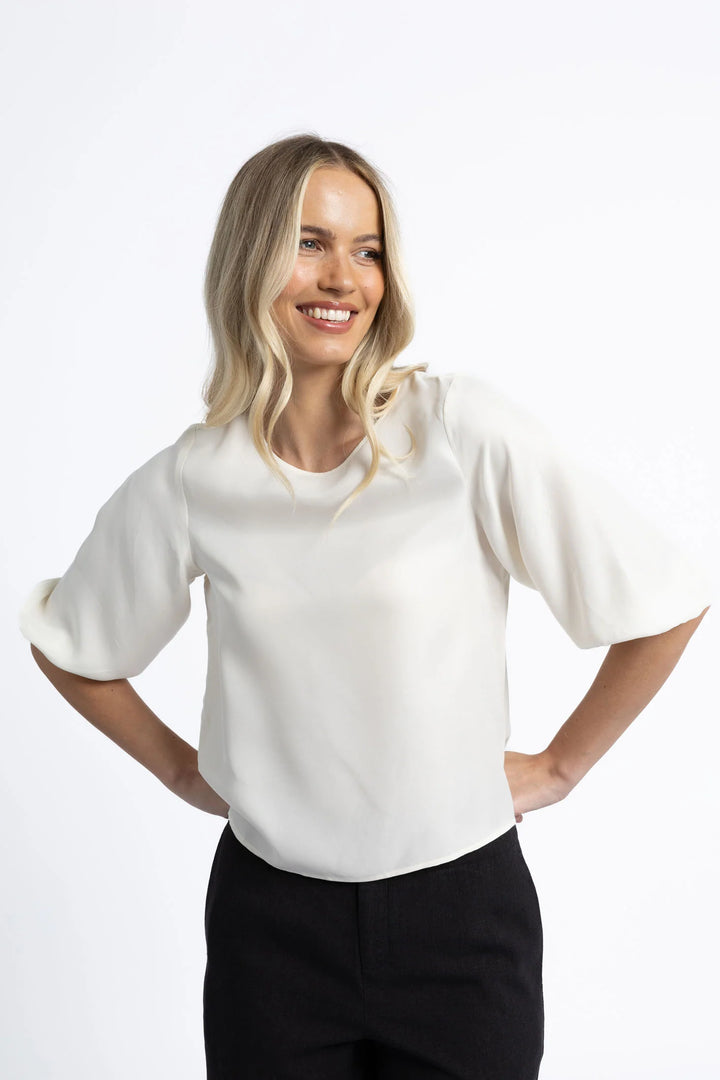 Woman wearing a white blouse and black pants on a white background