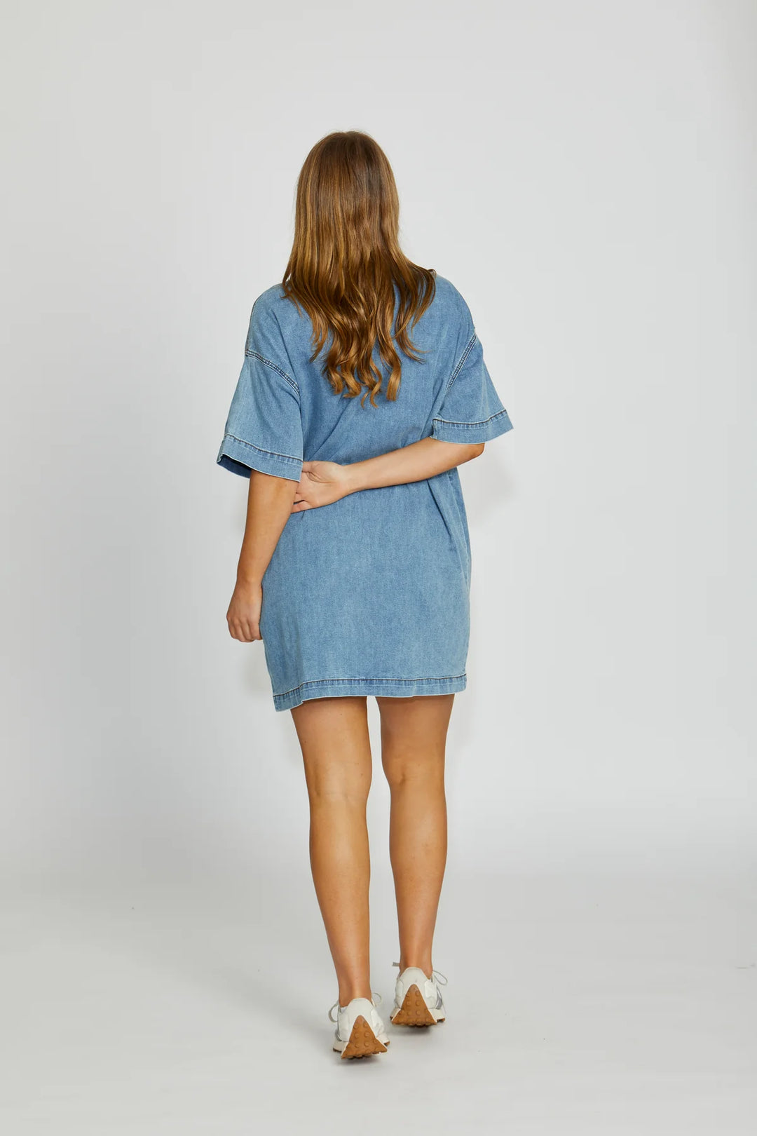 Woman wearing a denim dress on a plain background