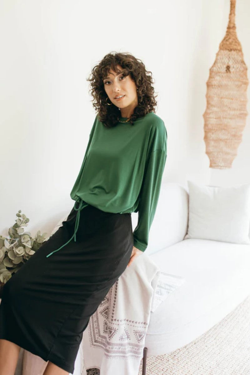 Lifestyle image of the Lady Drawstring Sweater in forest green, featured at Ivy Vibe, highlighting its relaxed fit and soft, eco-friendly fabric in a casual setting.