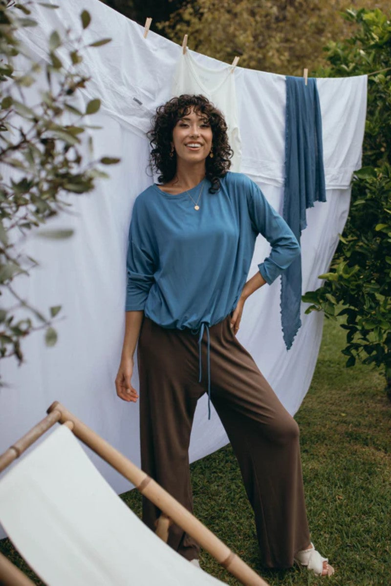 Lifestyle image of the Lady Drawstring Sweater in ocean blue, showcased at Ivy Vibe, featuring a relaxed fit and cozy, eco-friendly fabric in a casual setting.