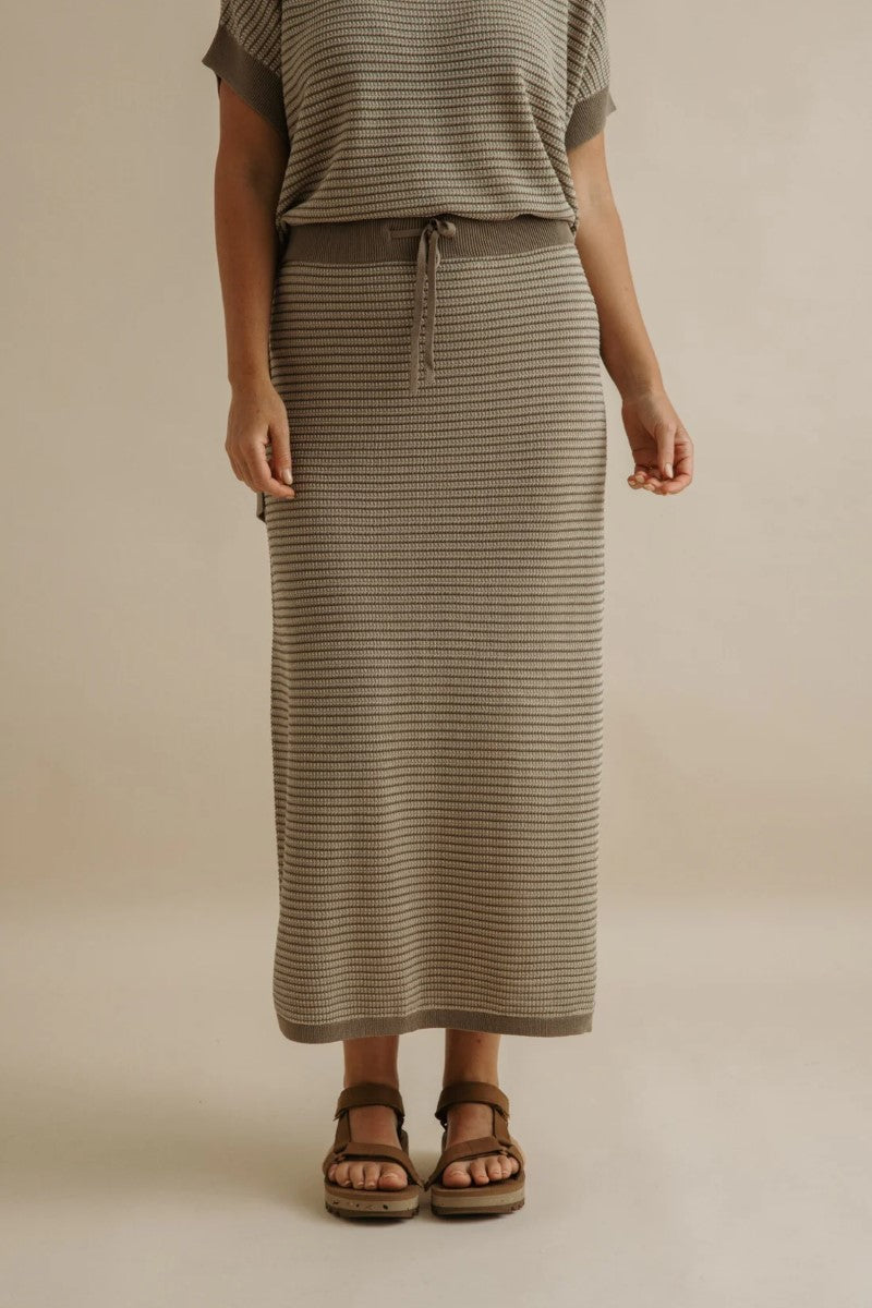 Person wearing a striped skirt and top on a beige background