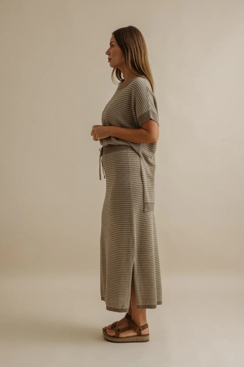 Woman wearing a striped dress against a beige background