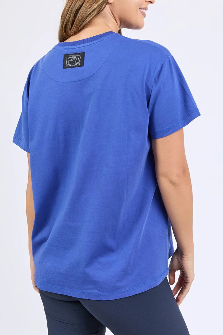 Person wearing a blue t-shirt with a logo on the back against a white background