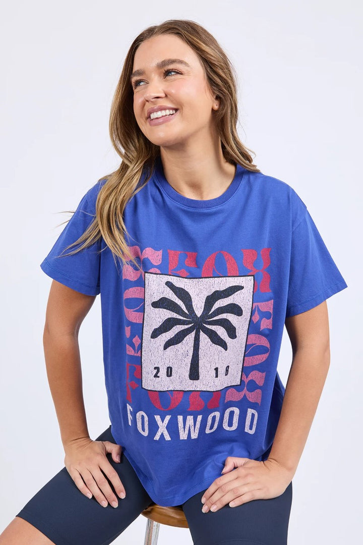 Woman wearing a blue t-shirt with a palm tree design and text on a white background