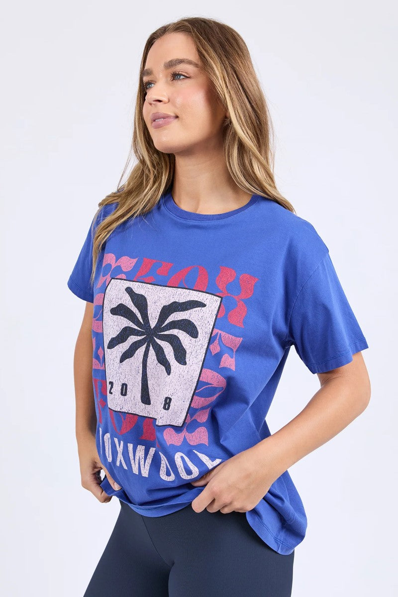 Woman wearing a blue graphic t-shirt with colorful design on a white background