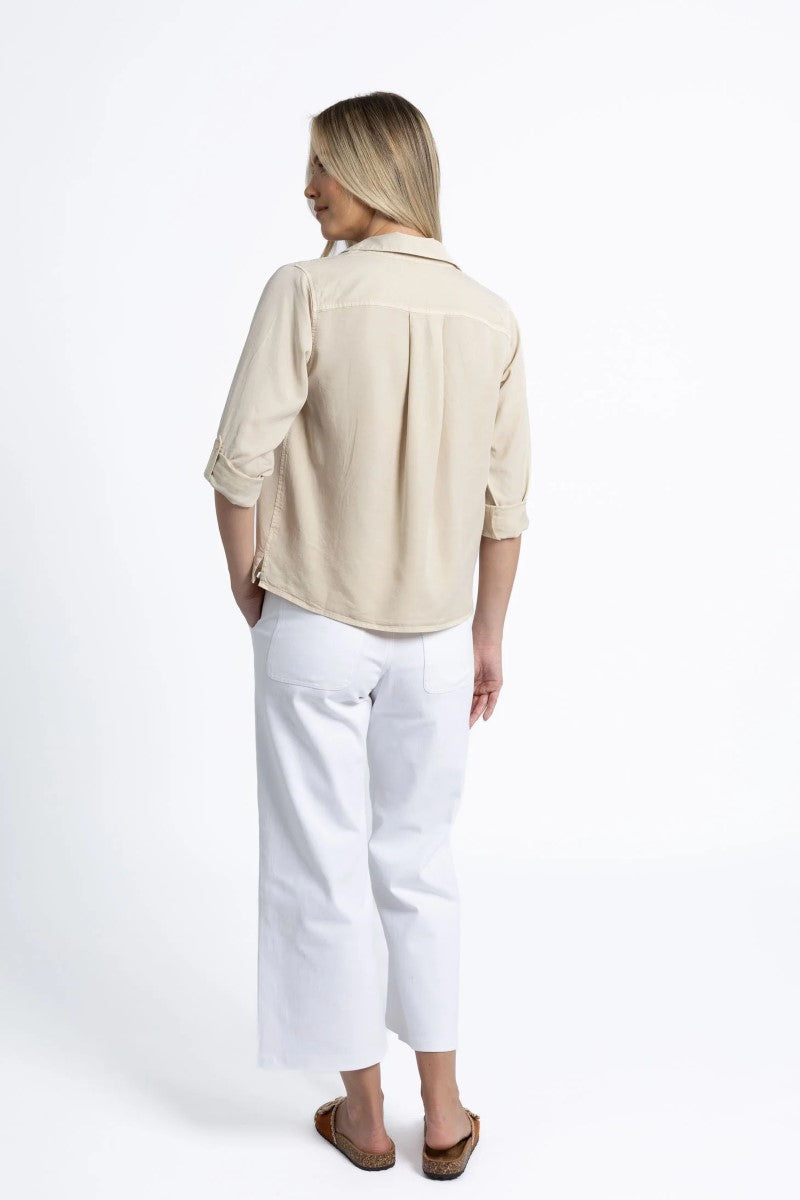 Person wearing a beige shirt and white pants on a white background