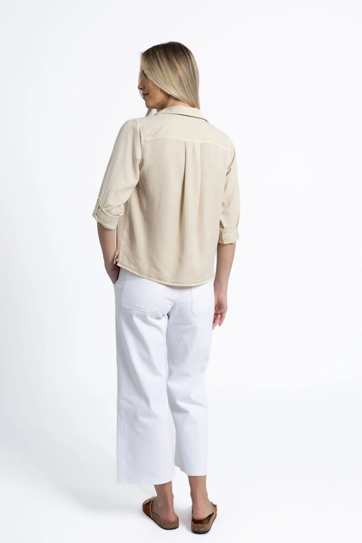 Person wearing a beige shirt and white pants on a white background