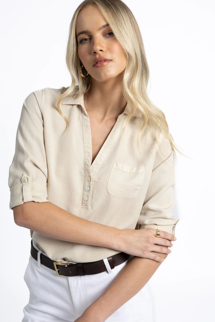 Woman wearing a beige blouse and white pants on a white background