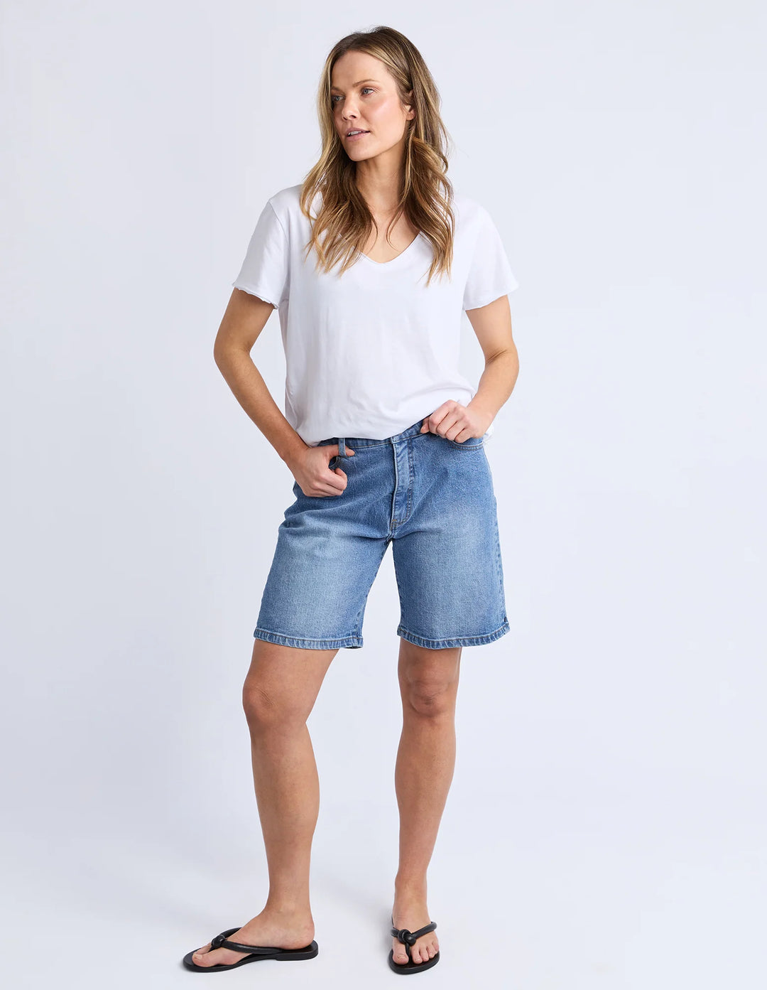 Woman wearing a white t-shirt and blue denim shorts on a white background