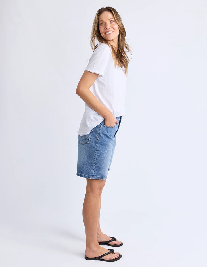 Woman wearing a white t-shirt and denim skirt on a plain background
