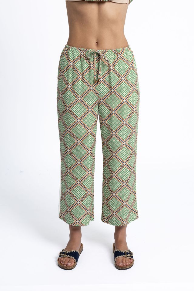 Green patterned pants worn by a person on a white background