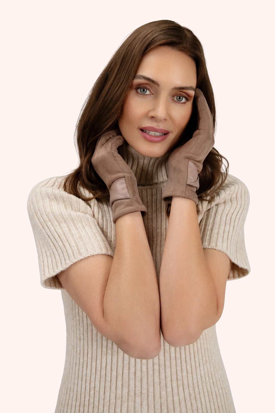 Woman wearing brown gloves and a beige sweater on a white background