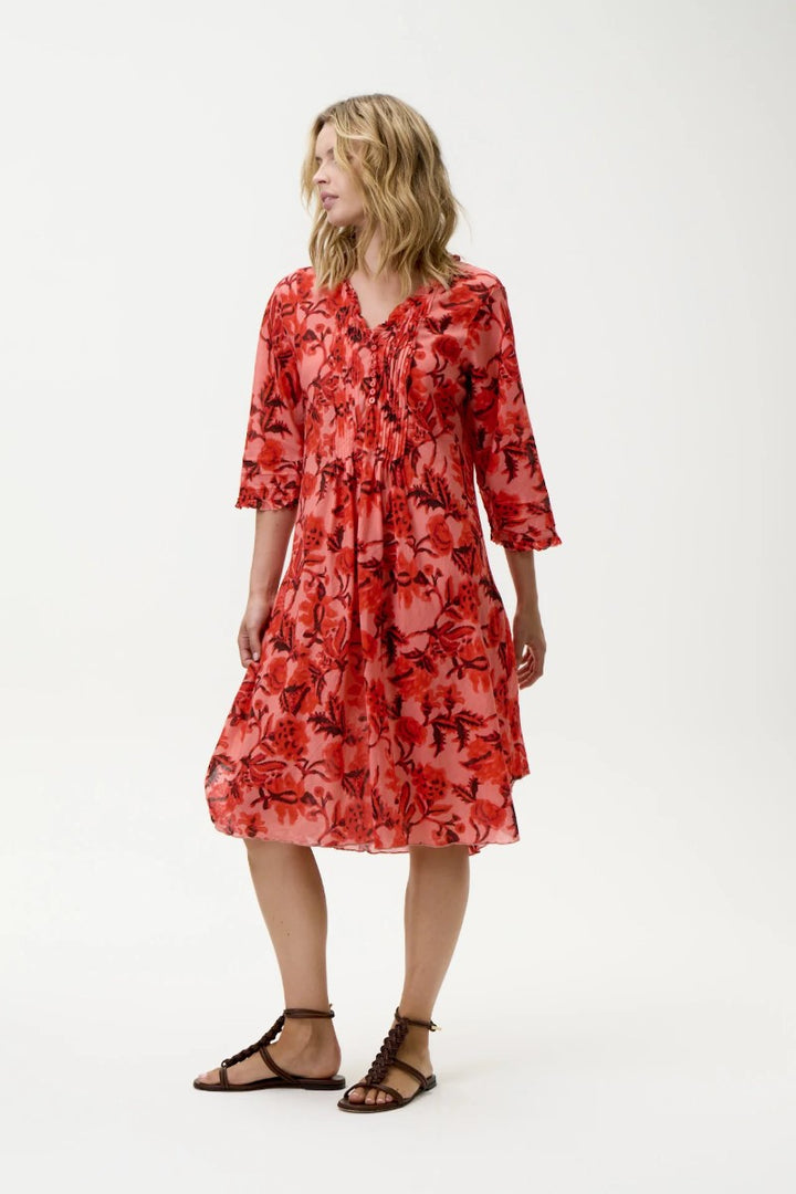 Woman wearing a red floral dress on a white background