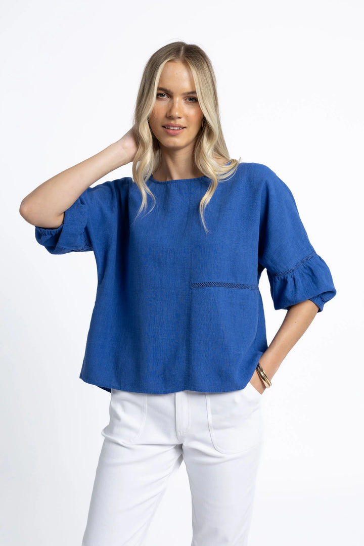 Woman wearing a blue blouse and white pants on a white background
