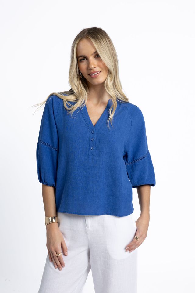 Woman wearing a blue blouse and white pants on a white background