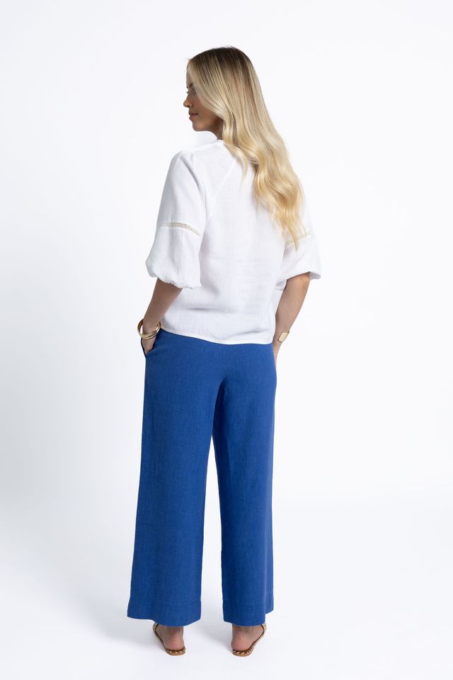 Woman wearing a white blouse and blue pants on a white background