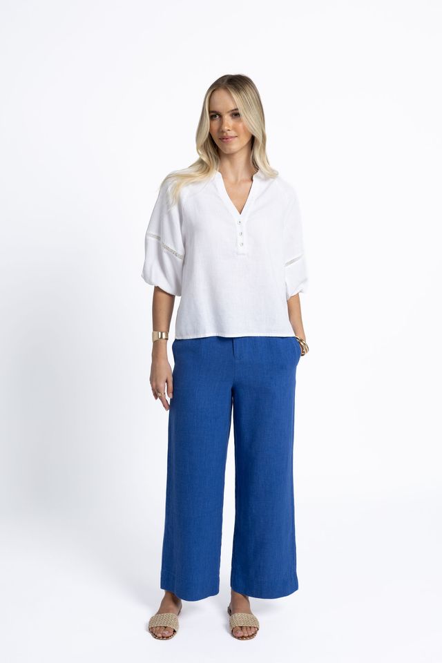 Woman wearing a white blouse and blue pants on a white background