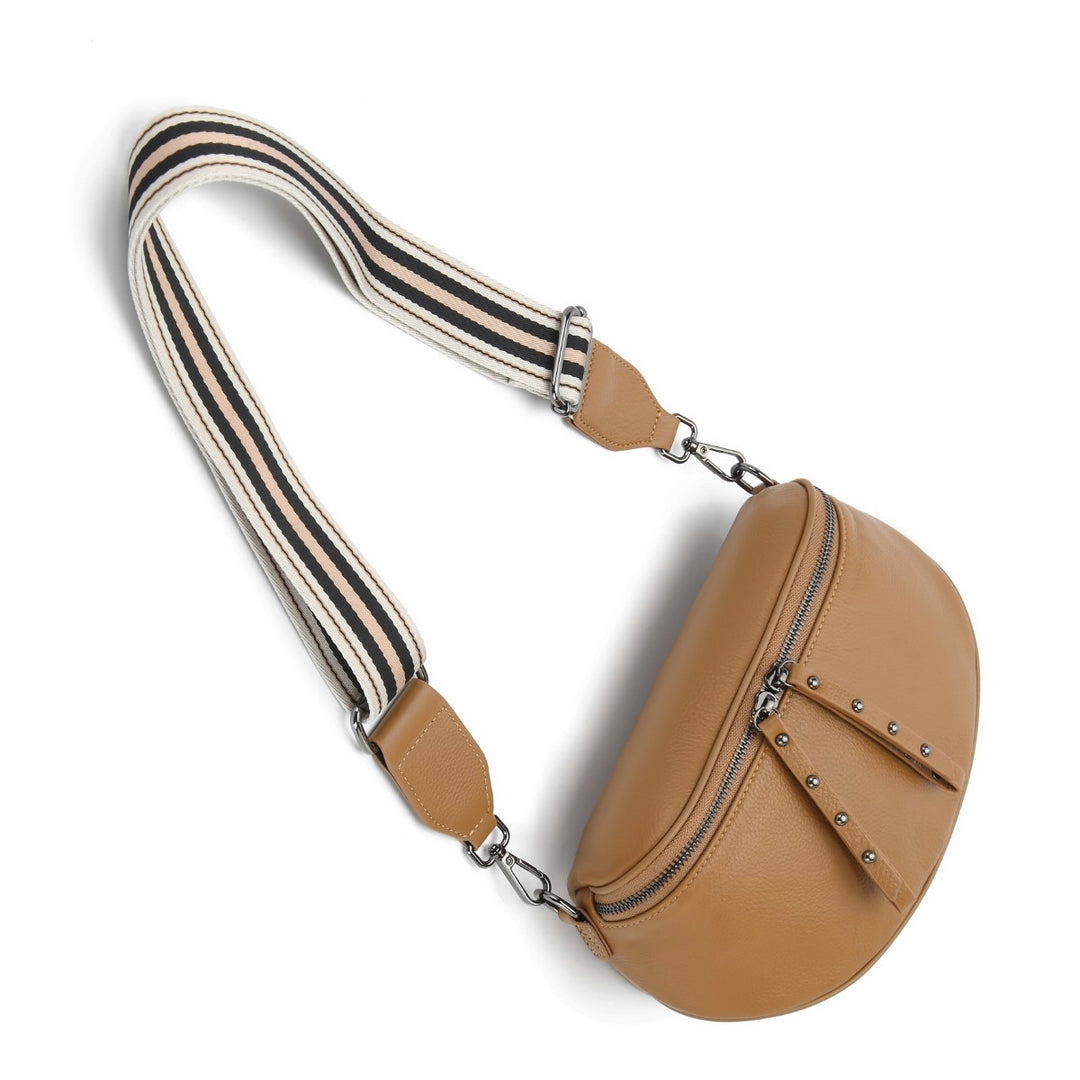 The Obsessed Bag is crafted in soft camel leather with gunmetal hardware, featuring a wide detachable strap and secure zip details, available at Ivy Vibe.