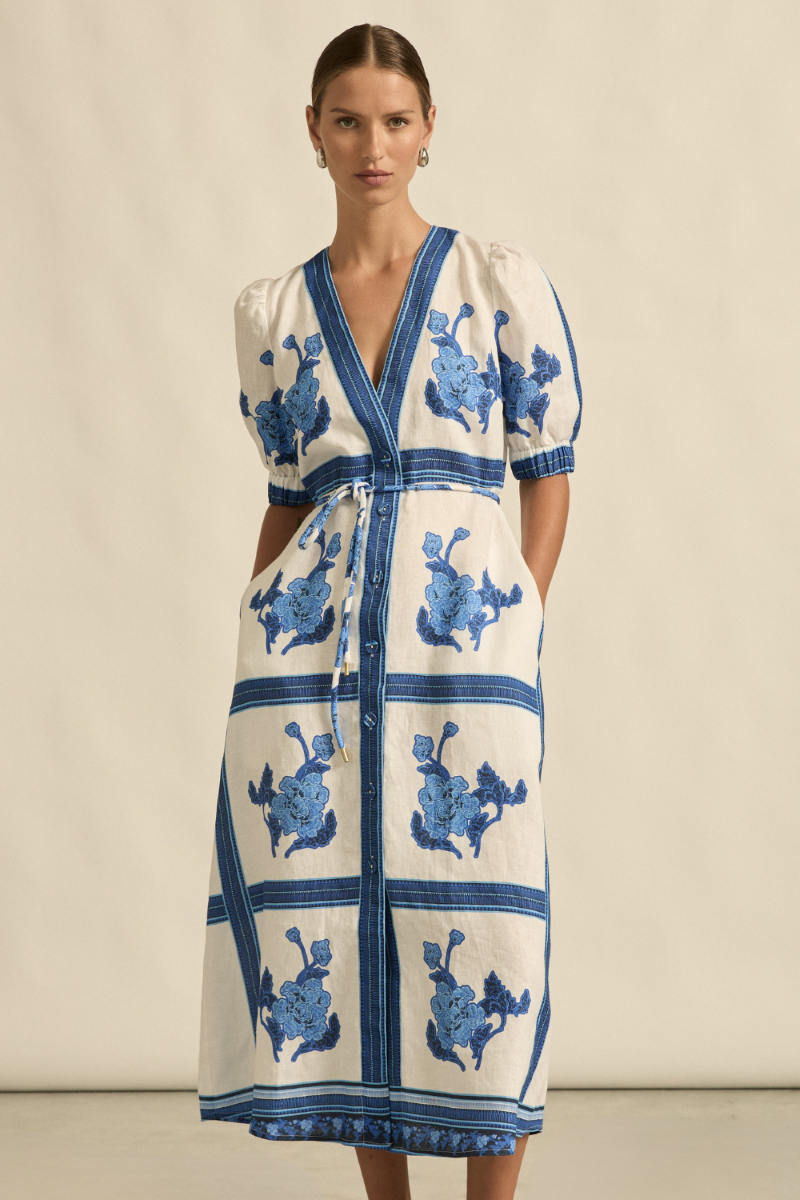 This front view of the Portrait Dress in Azure Collage highlights its sleek A-line silhouette, V-neckline with covered buttons, and elegant self-tie belt detail.