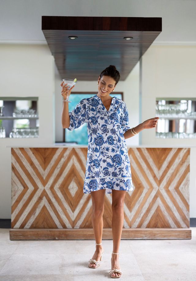 Woman in a blue floral dress standing in a modern kitchen.