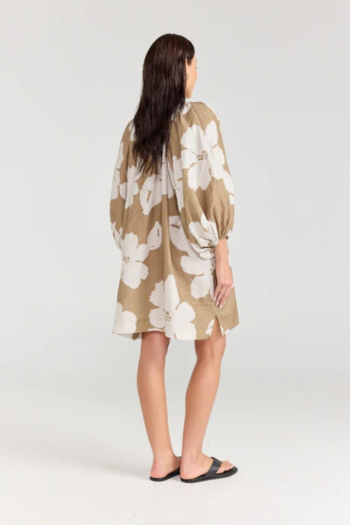 Woman wearing a beige floral dress on a white background