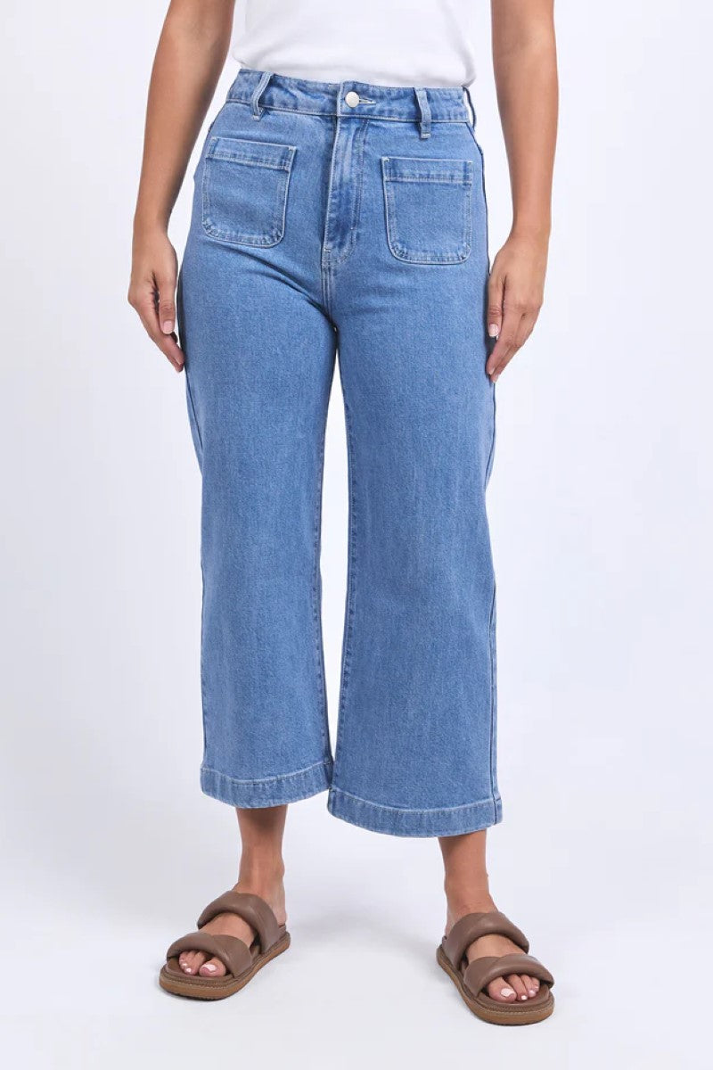 Person wearing blue jeans and brown sandals on a white background