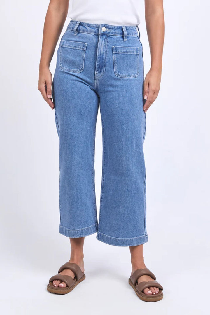 Person wearing blue jeans and brown sandals on a white background