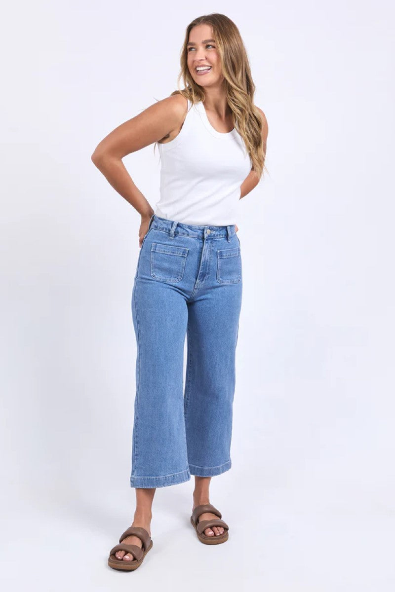 Woman wearing a white tank top and blue jeans on a white background