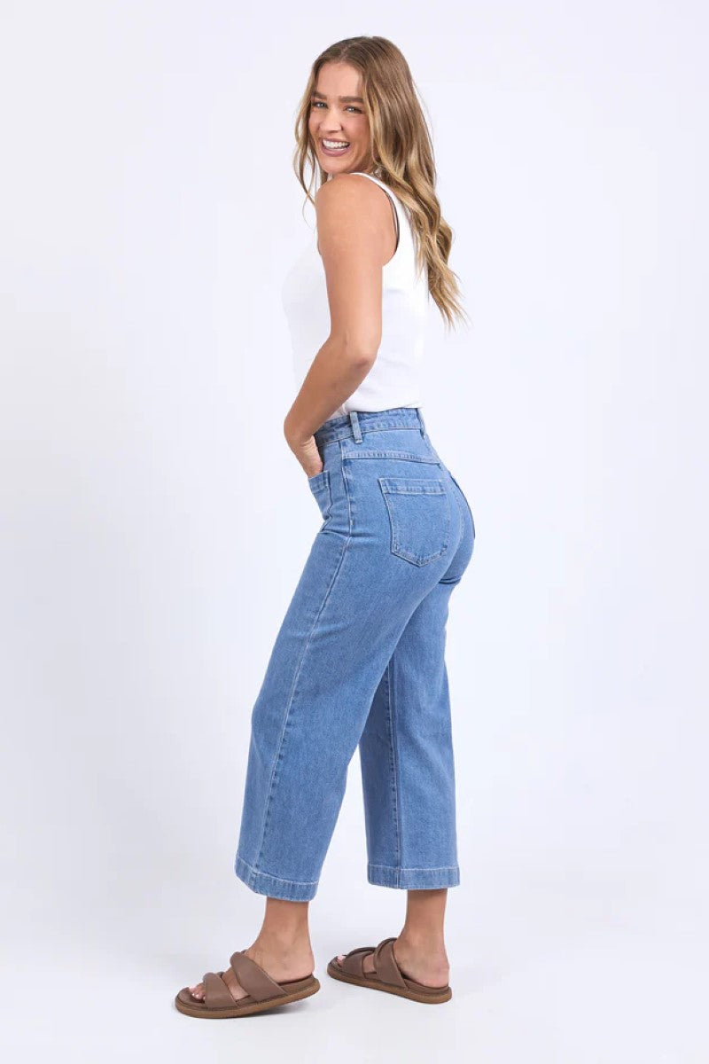 Woman wearing light blue jeans and a white top on a white background